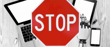 mani di robot su computer e cartello stop