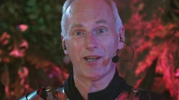 uomo con capelli bianchi e micrfono con corazza