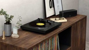 giradischi nero sony sopra mobile in legno accanto a cornice